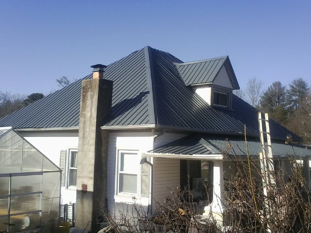 Dark blue standing seam metal roof on a white farmhouse with dormer — Slate & Tile Roof Repair by Roofing Brothers in Norco