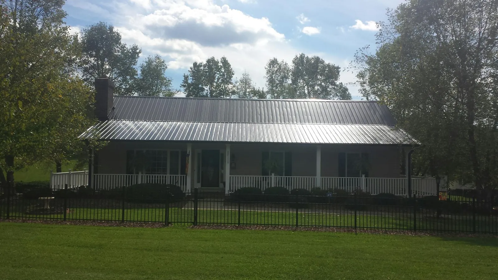 Gray metal roof on a brick ranch with a full width front porch — Gutter Guard Installation work by our crew in Norco